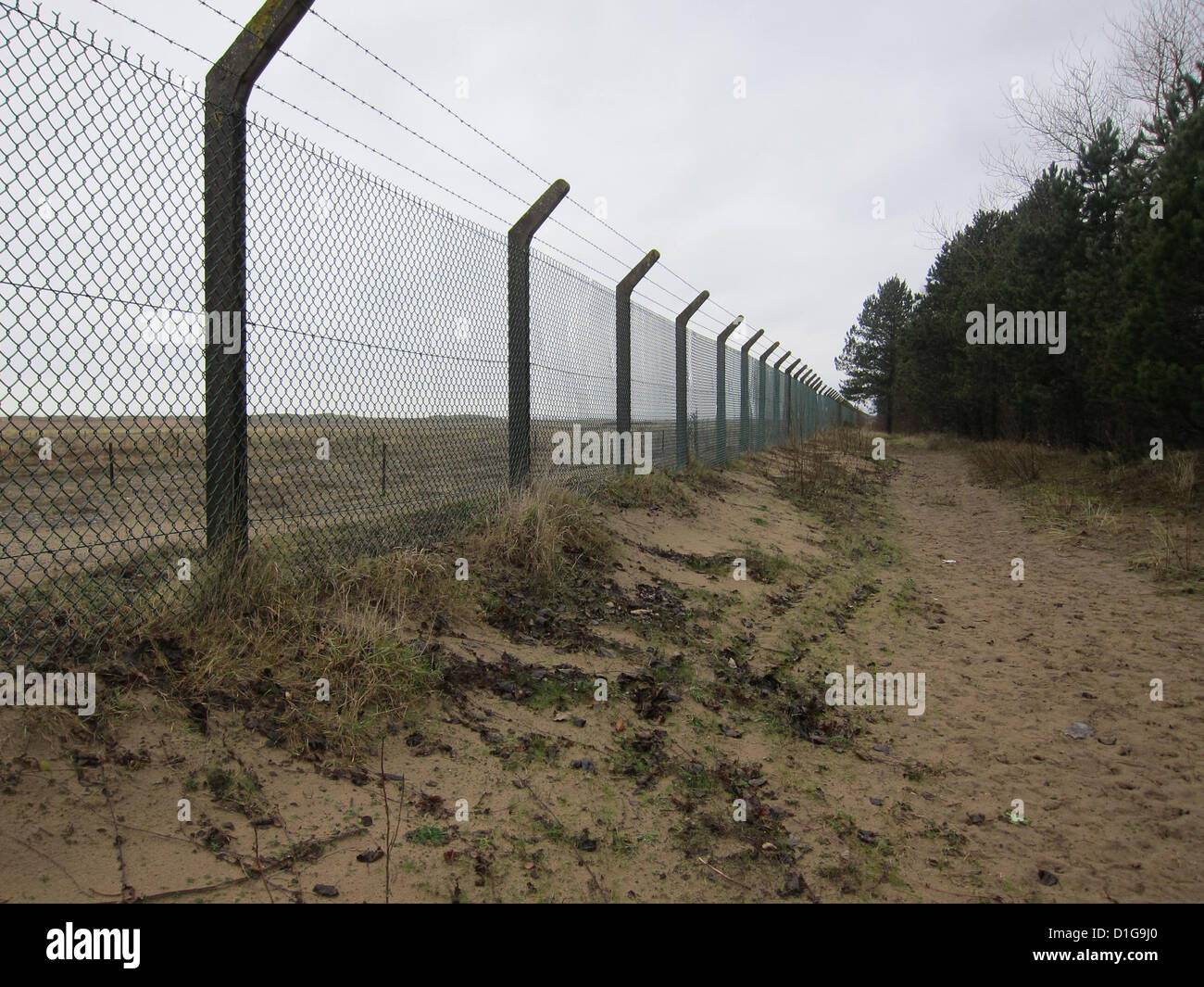 Sur le fil de la clôture de sécurité autour d'une parcelle de terre vide, près de Swansea, Pays de Galles du Sud, Décembre 2012 Banque D'Images