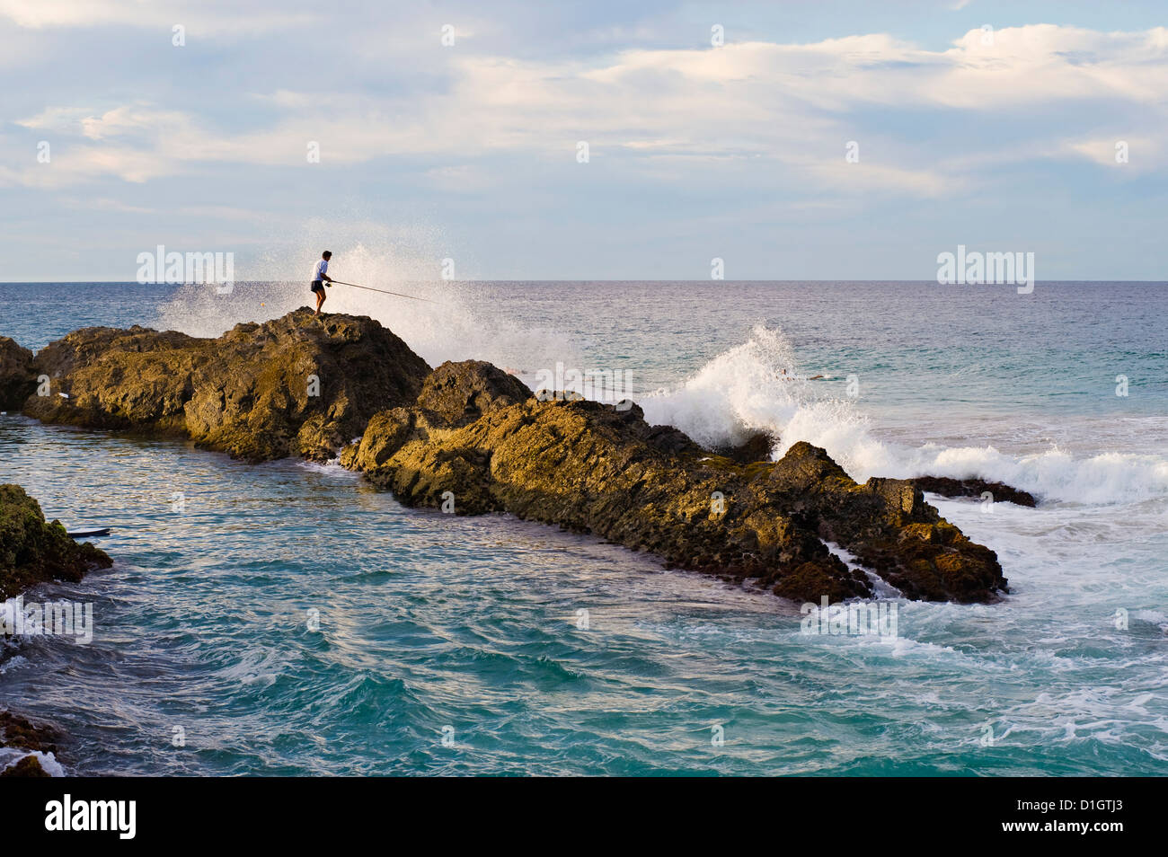 Fisherman se faire frapper par une vague alors que la pêche rock à Snapper Rocks, Tweed Heads, Gold Coast, Queensland, Australie, Pacifique Banque D'Images