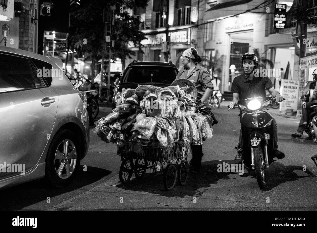 Homme vietnamien dépasse un vendeur de rue dans l'un des vieux quartiers de Hanoi Vietnam routes Banque D'Images