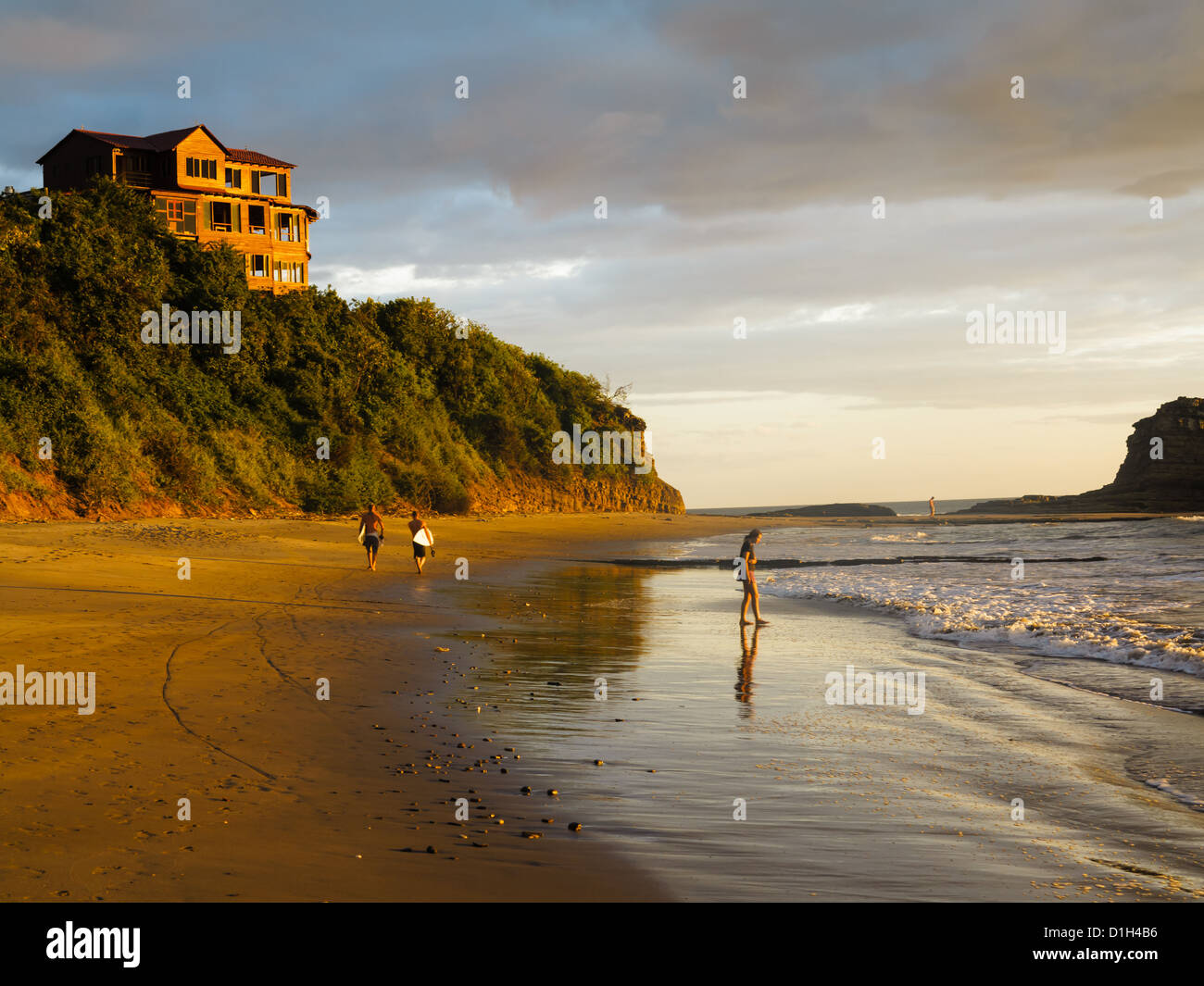 Deux hommes à pied de la plage de surfers sur l'exécution des planches pendant qu'une personne se trouve dans l'eau au Nicaragua à marée basse Banque D'Images