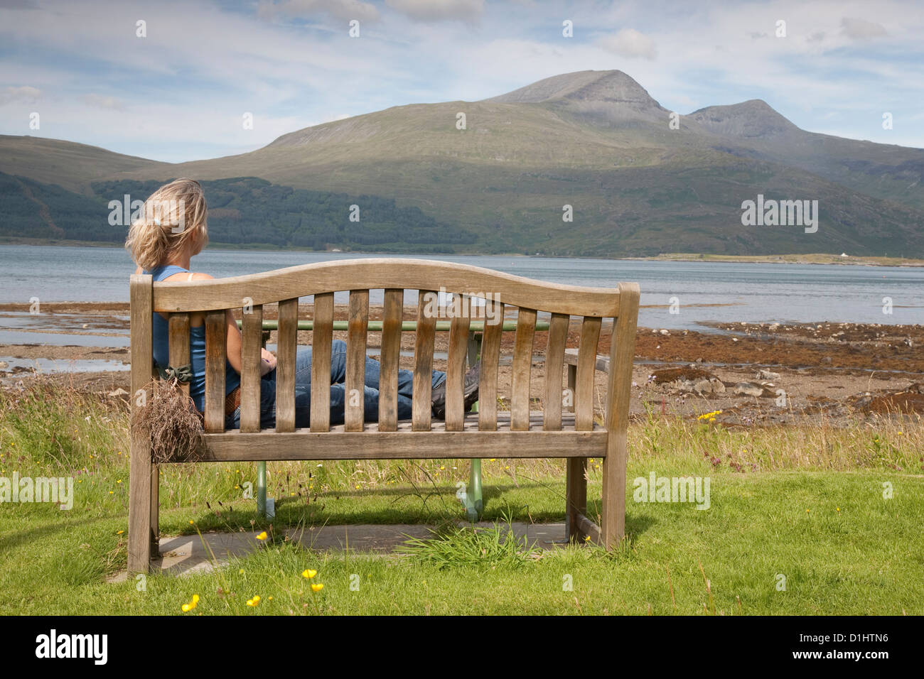 Jeune femme assise sur un banc sur l'île de Mull, en Ecosse Banque D'Images