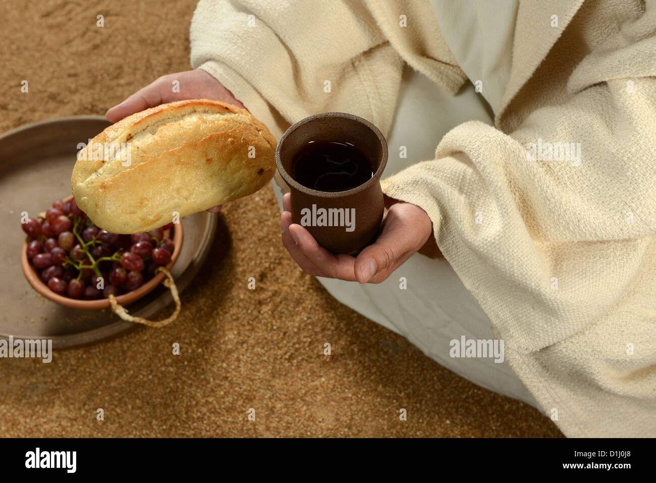 Jésus mains tenant le pain et le vin avec le bac de raisins en arrière-plan Banque D'Images