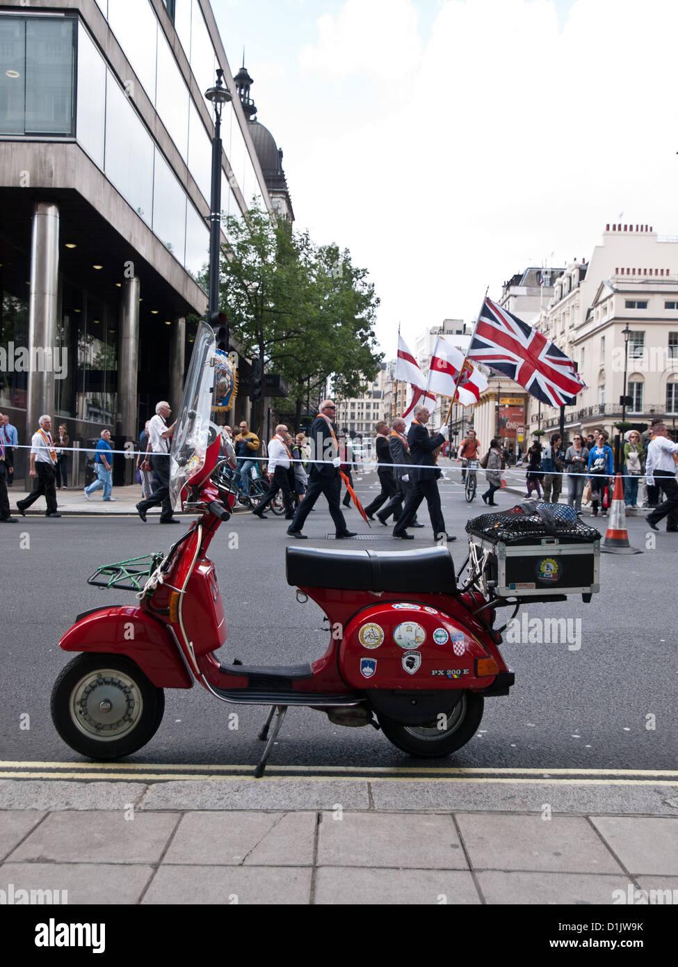 Un ordre d'Orange défilent dans les rues de Londres, au cours de l'été 2012. Un Vespa rouge est garée à l'avant-plan. Banque D'Images