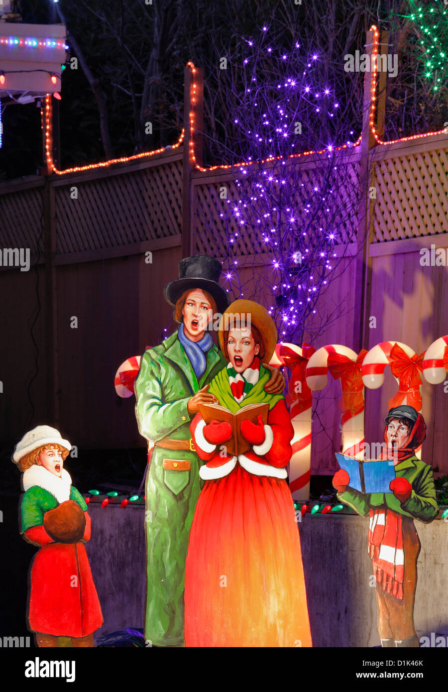 Figurines de Noël caroller en face de la maison illuminée pour les fêtes de Noël.-Victoria, Colombie-Britannique, Canada. Banque D'Images