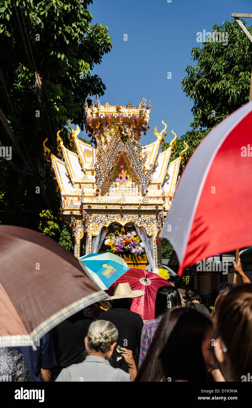 Parapluies de personnes en procession à la suite de hauteur richement décorés funérailles bouddhistes flottent parade à Chiang Mai Thaïlande Banque D'Images