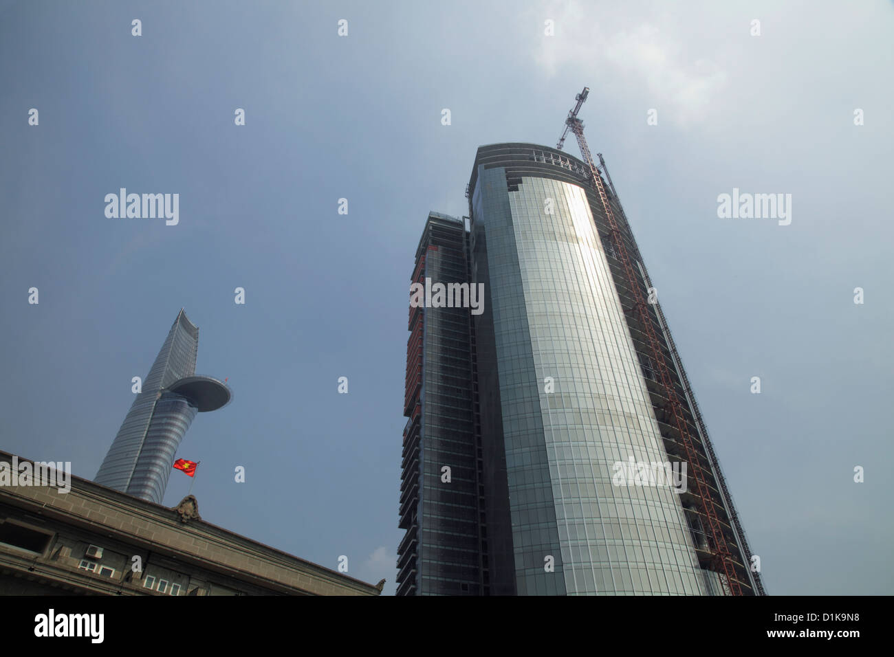L'angle faible de ce gratte-ciel moderne en cours de construction et Bitexco Financial Tower en arrière-plan. Ho Chi Minh, Vietnam Banque D'Images