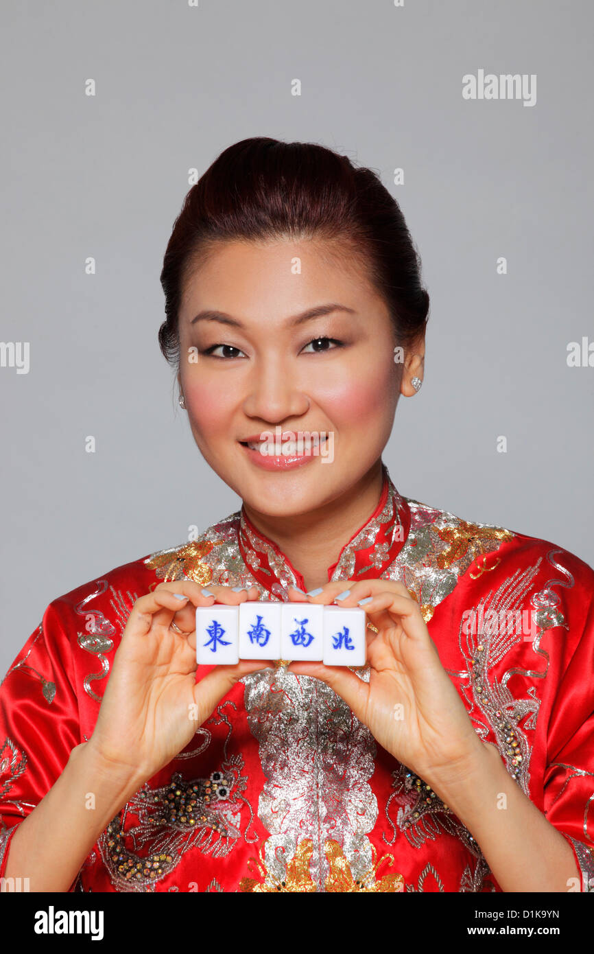 Woman holding Cheongsam Mahjong tiles avec les personnages pour Sud, Est, Ouest, Nord Banque D'Images
