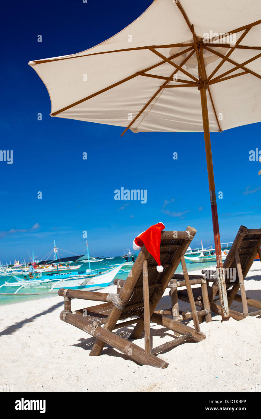 Parasol avec Santa Claus Hat sur des chaises sur la plage tropicale Banque D'Images