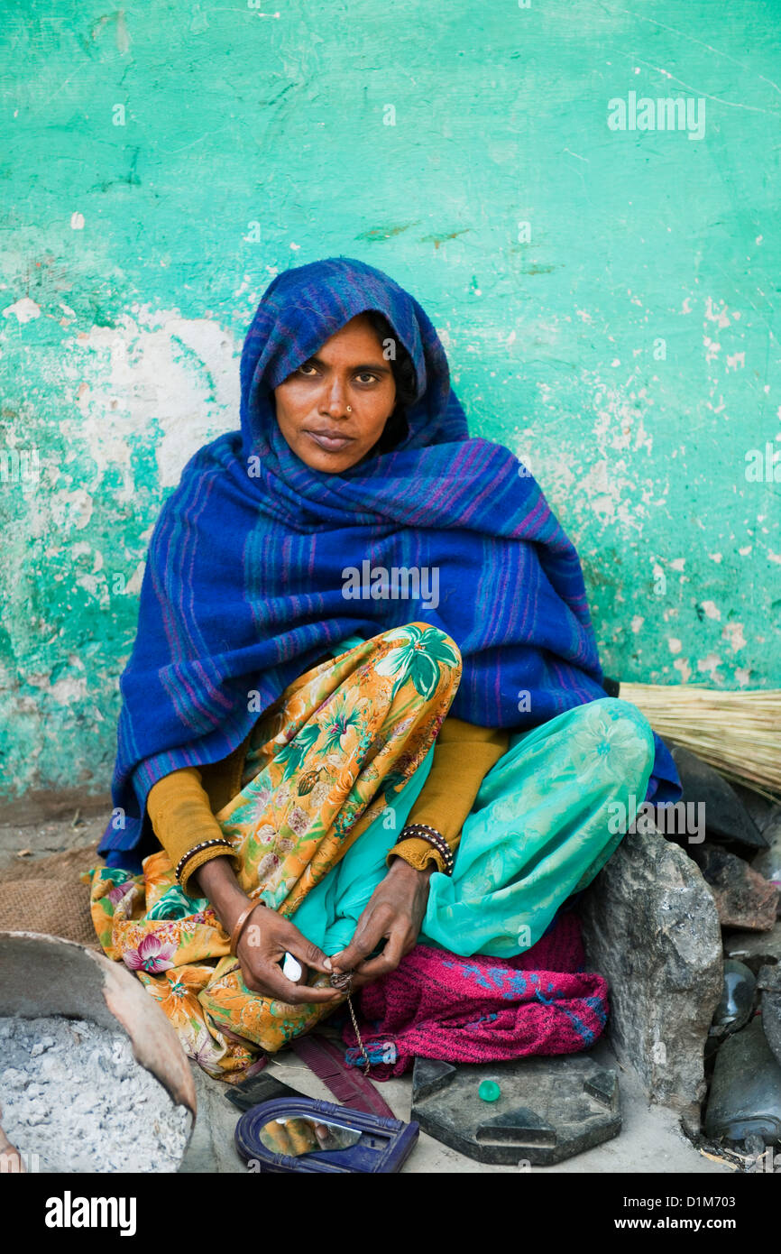 Une femme indienne dans un châle bleu se trouve à l'extérieur sa maison contre un mur vert l'application de faire lever le matin dans le Rajasthan en Inde Banque D'Images