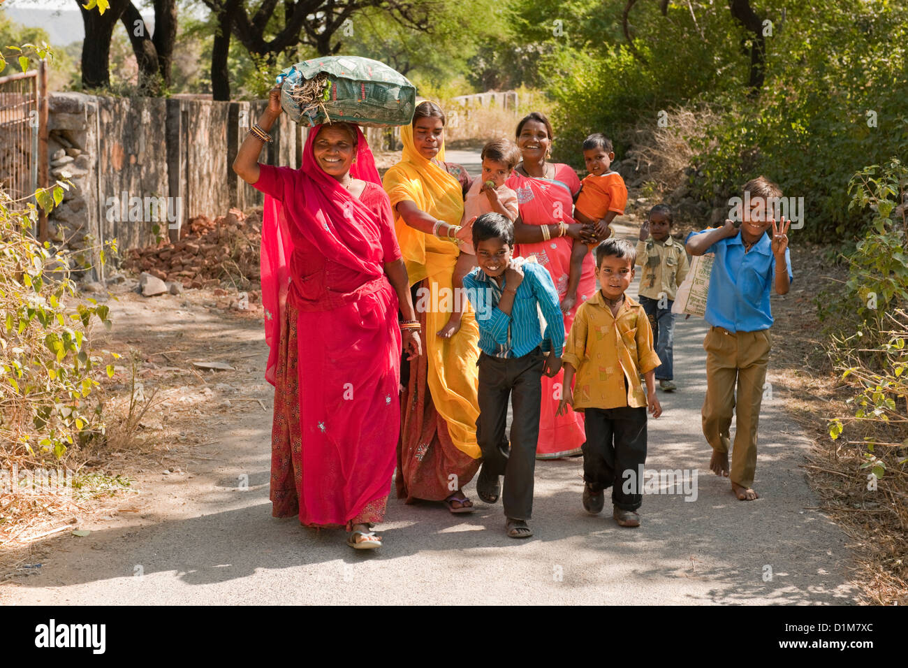 Une famille d'Indiens colorés happy smiling groupe de femmes garçons filles et un bébé de retour de shopping dans une rue calme, dans l'Asie de l'Inde Banque D'Images