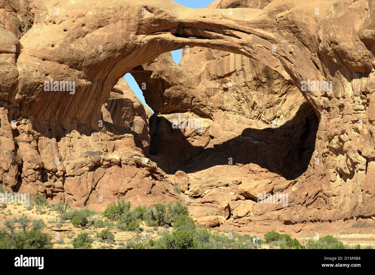 Arc double, Arches NP, près de Moab, Utah, aux Etats-Unis. Arch Rock double formation géologique avec les touristes en premier plan pour montrer l'échelle Banque D'Images