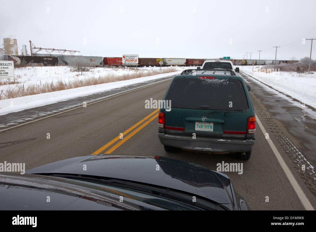 En attendant les voitures du train traversant l'autoroute trans-Canada en hiver à l'extérieur de Yorkton en Saskatchewan Canada Banque D'Images
