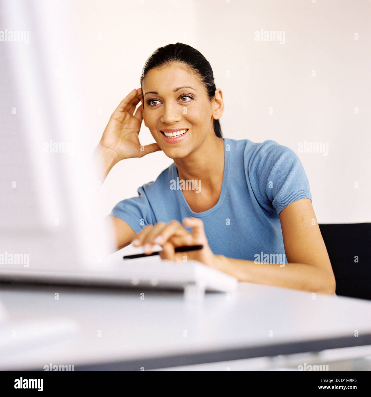 Businesswoman in office looking at computer smiling Licence gratuite à l'exception des annonces et affiches Banque D'Images