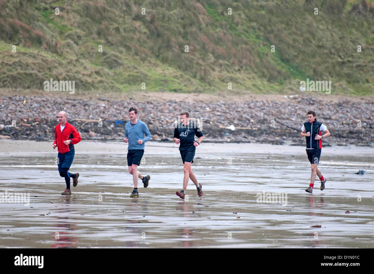 Rhossili Beach, près de Swansea, Royaume-Uni. 30 déc, 2012. Un groupe de joggeurs bravant la pluie et la tempête le long de la rive du Rhossili Beach sur la péninsule de Gower, près de Swansea ce matin. Banque D'Images