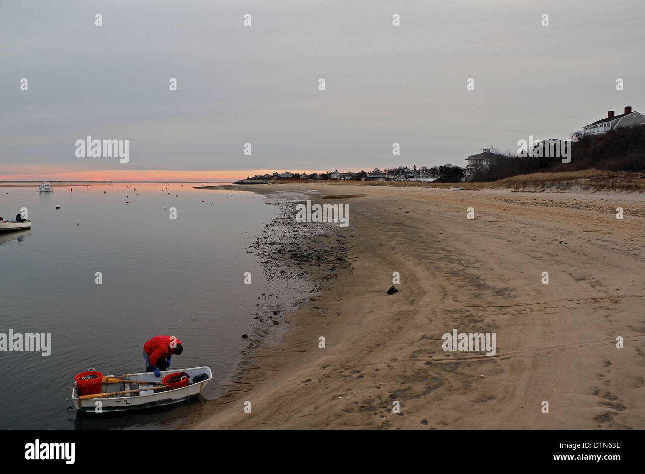 Un homme apporte un petit bateau à la rive au coucher du soleil près de l'Embarcadère de Chatham, Cape Cod, Massachusetts Banque D'Images