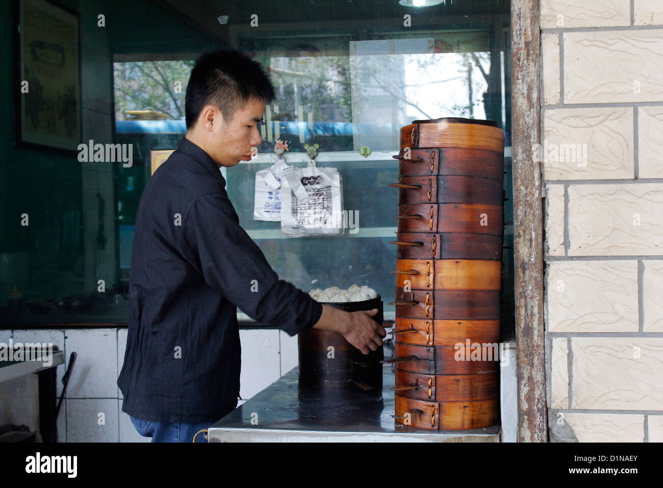 Un homme chinois cuisine chinoise traditionnelle des dim sum (raviolis chinois) dans des paniers vapeur en bambou Banque D'Images