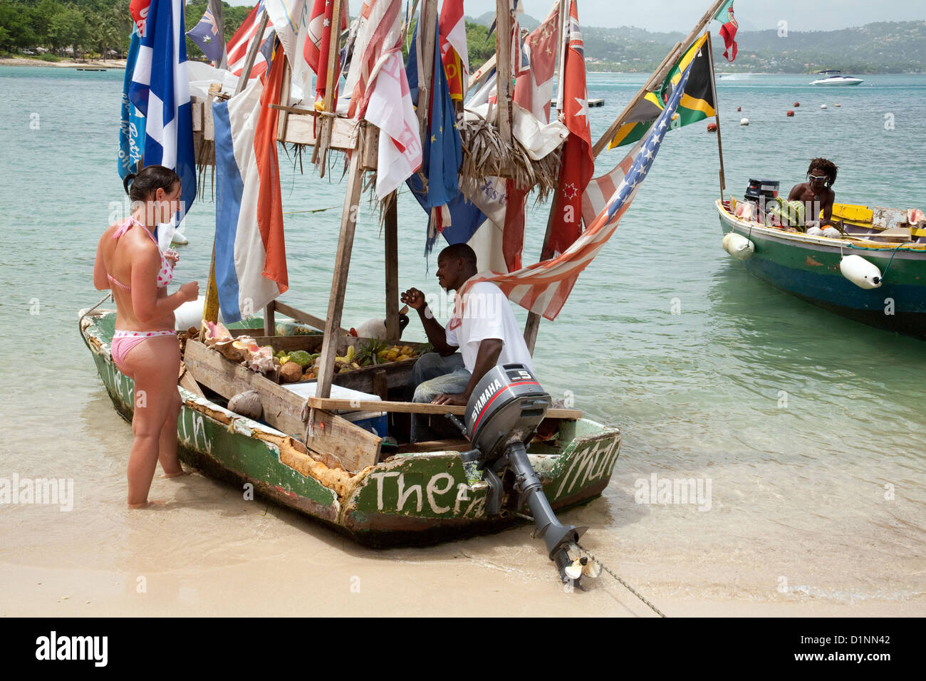 Le tourisme des Caraïbes; Une femme touriste achetant des fruits d'un commerçant local, vendant de son bateau, Windjammer Landing plage, Sainte-Lucie, Caraïbes Antilles Banque D'Images