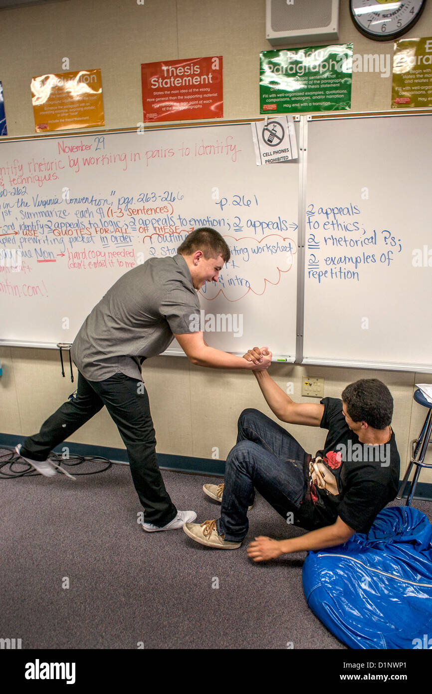 Deux élèves du secondaire exubérante Californie arm wrestle pendant un cours d'anglais. Banque D'Images