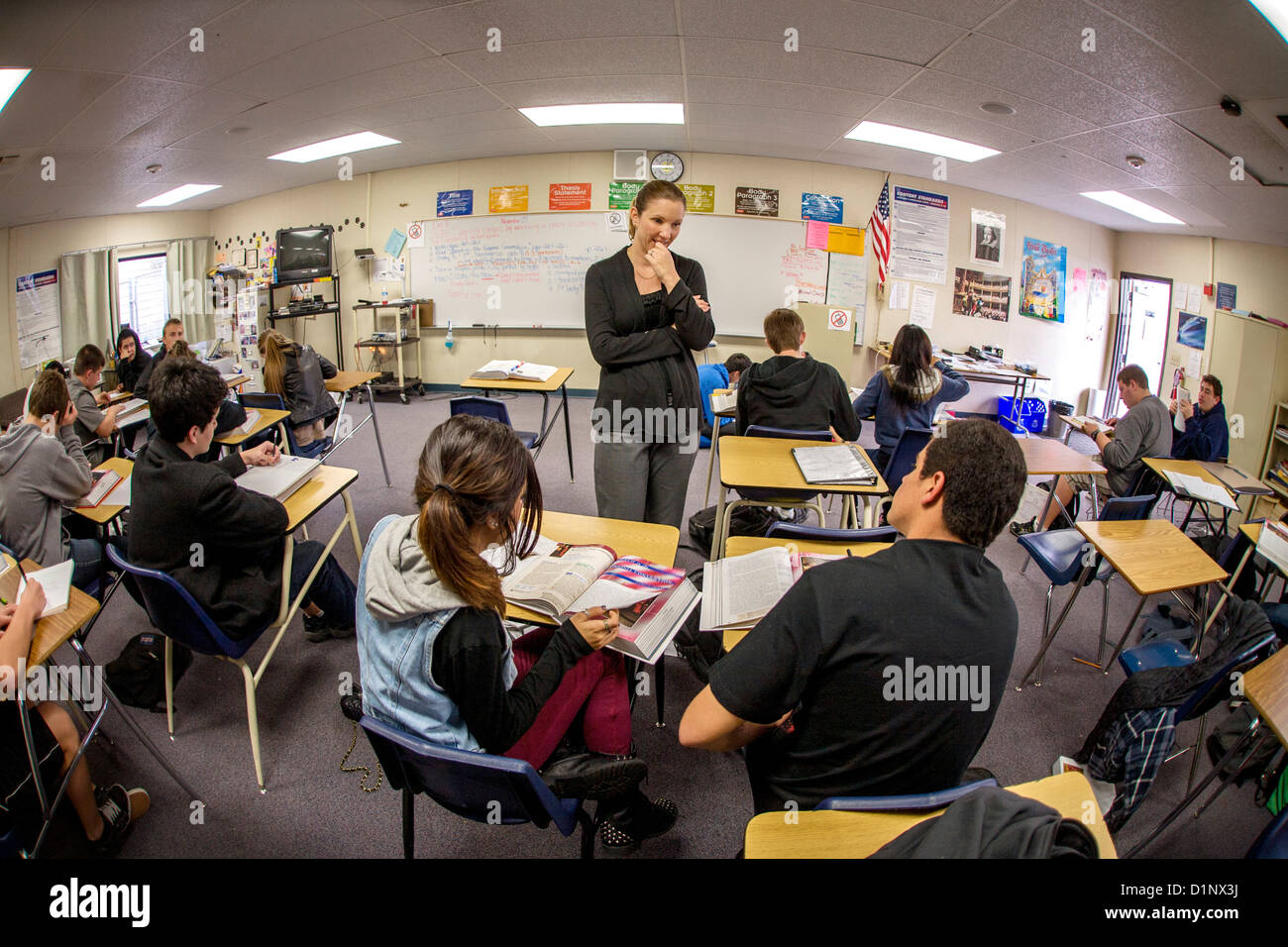 La California high school professeur de français aide son comprendre aux élèves les pendant un exercice de lecture à l'aide d'anthologie littéraire. Banque D'Images