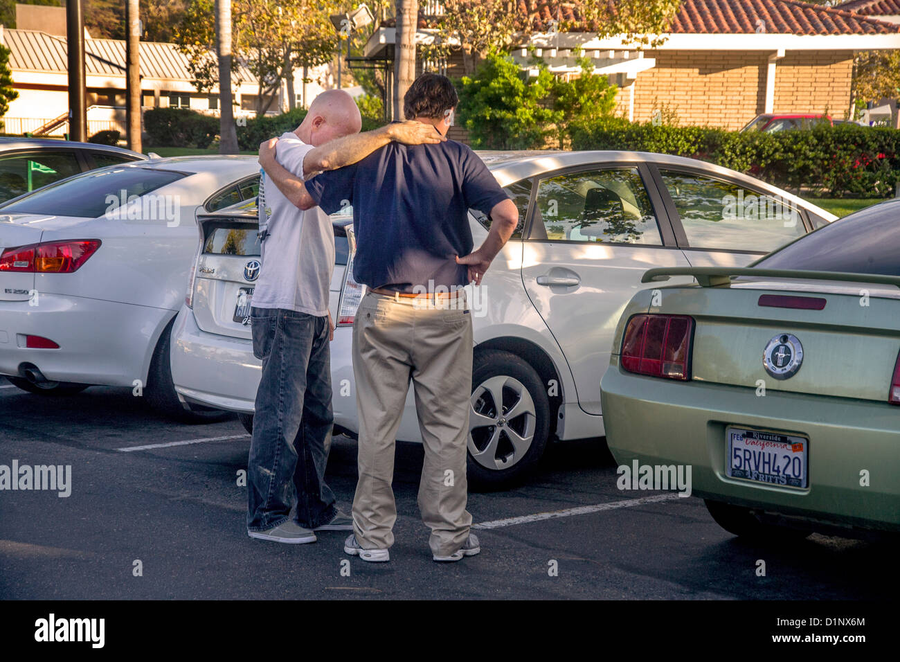 Bras dessus bras dessous, deux hommes prier ensemble dans une Laguna Niguel, CA, un parking. Banque D'Images