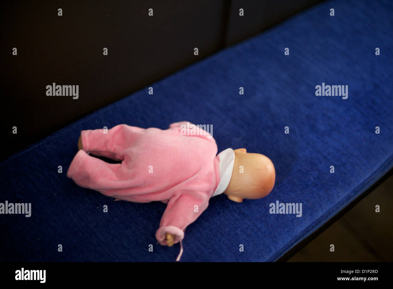 Baby doll face vers le bas sur un tapis bleu avec étape dans un seul costume rose tous les Banque D'Images