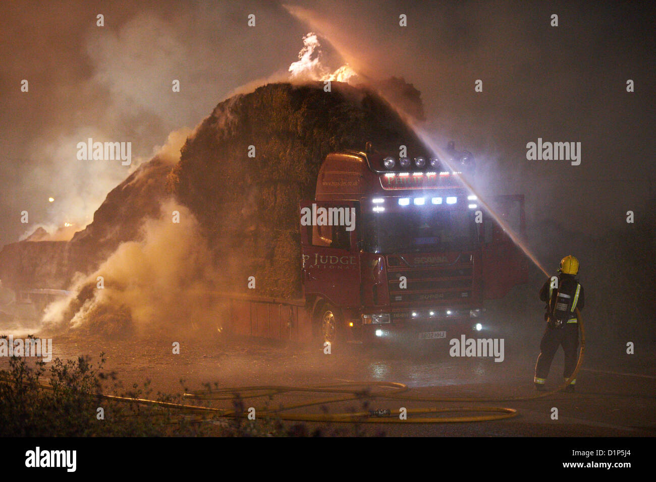Les pompiers portent sur un grand camion de foin le feu sur l'A41 près de Aston Clinton Banque D'Images