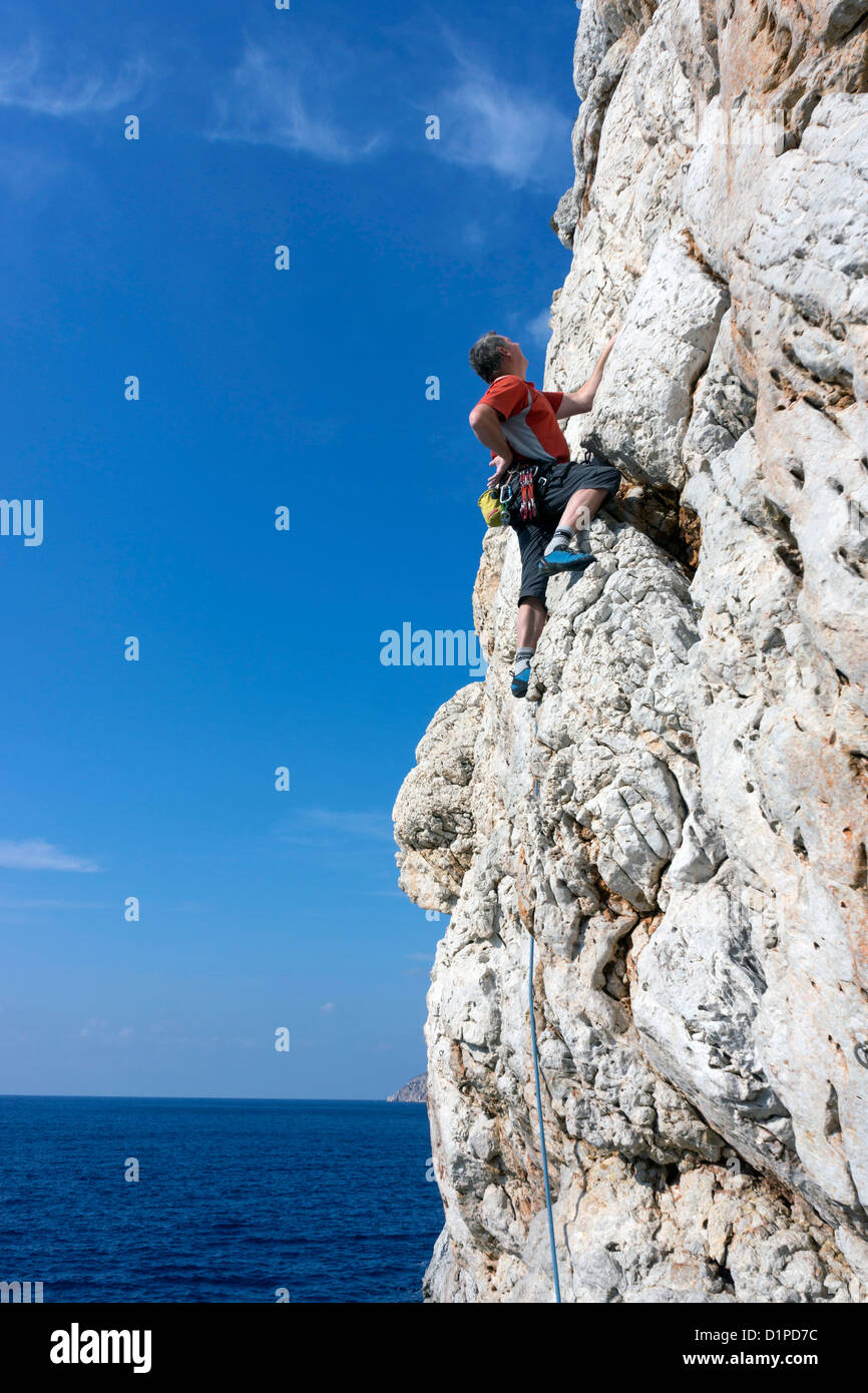 Male rock climber wearing red sur falaise, Kalymnos, Grèce Banque D'Images