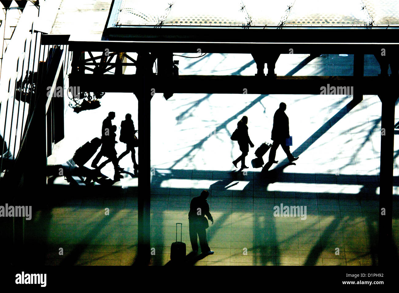 Les voyageurs arrivant à l'aéroport d'Heathrow, Terminal 5, en silhouette, marche à pied avec leurs bagages Banque D'Images