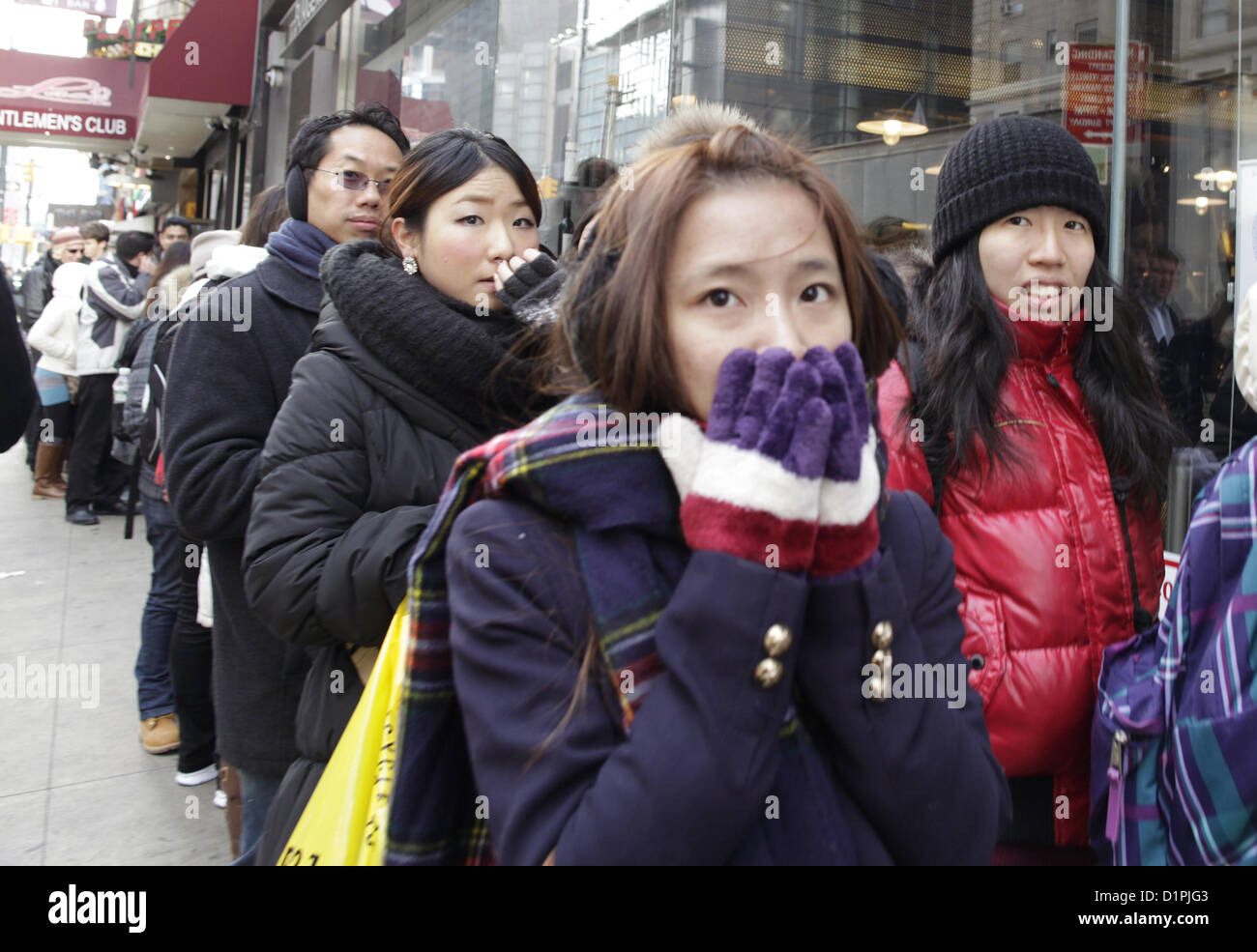 Les touristes japonais supporter le froid soudain de froid tout en faisant la queue pour un restaurant dans la ville de New York. Banque D'Images