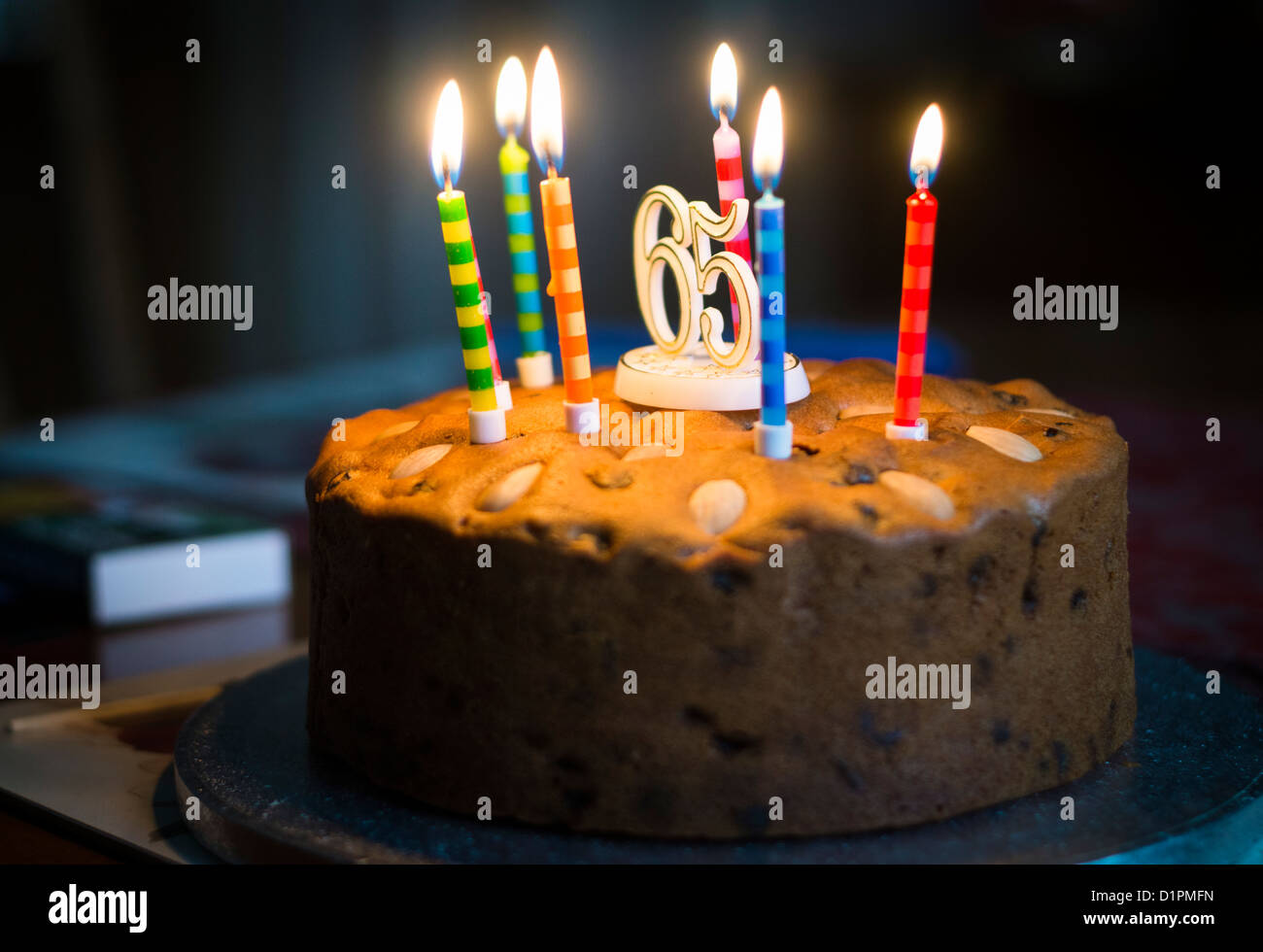 Allumé des bougies sur un gâteau célébrant le 65e anniversaire et la retraite. Banque D'Images