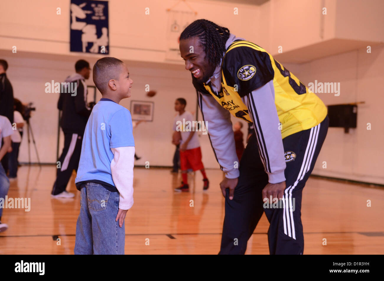 Torrodney Prevot, joueur de ligne défensive de l'équipe Ouest, interagit avec un enfant de sa Youth à l'église méthodiste Paul United à San Antonio, Texas, le 2 janvier 2013. Sa Youth offre des programmes de développement pour les jeunes à risque. Le U.S. Army All-American Bowl sélectionne les meilleurs joueurs de football du secondaire pour participer à l'événement. Banque D'Images
