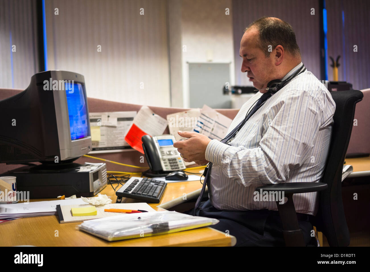 Businessman with ventre ballonné s'assit à son bureau. Banque D'Images
