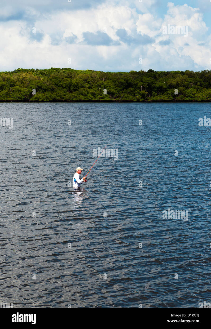Un homme d'une pataugeoire et de pêche dans la voie navigable côtière entre la Floride. Banque D'Images