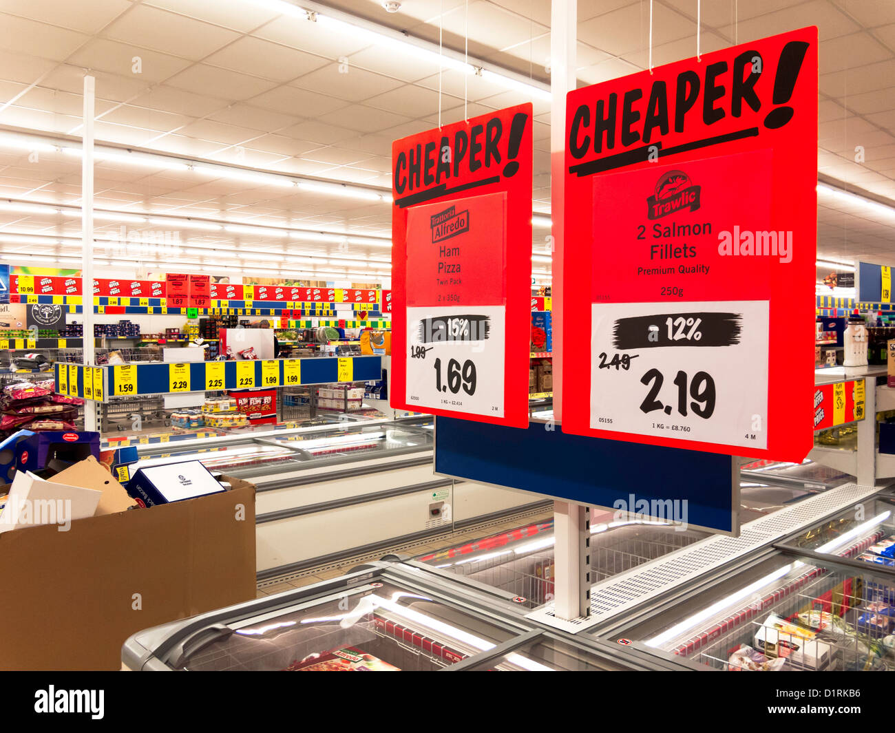 Moins cher ! Moins cher ! Grosse orange signes promotionnels dans la section des aliments d'un supermarché Lidl Banque D'Images