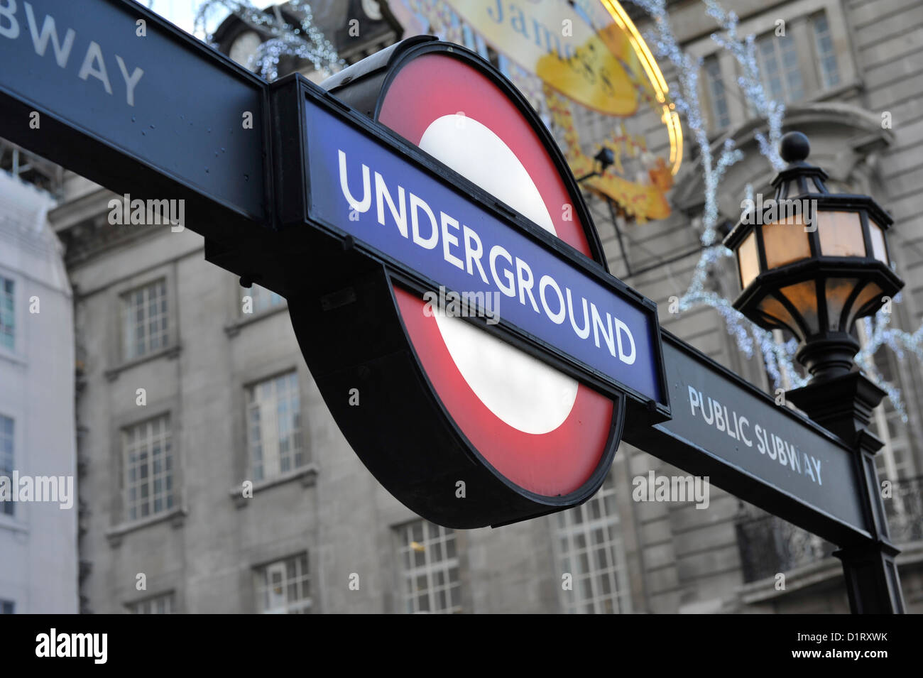 London Underground tube signe. Des lueurs de la ville derrière. Banque D'Images