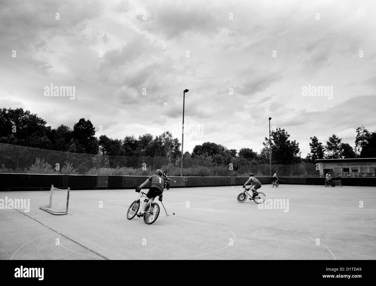 Grand angle d'une photo en noir et blanc de bike polo joueurs sur une patinoire fermée un jour nuageux. Banque D'Images