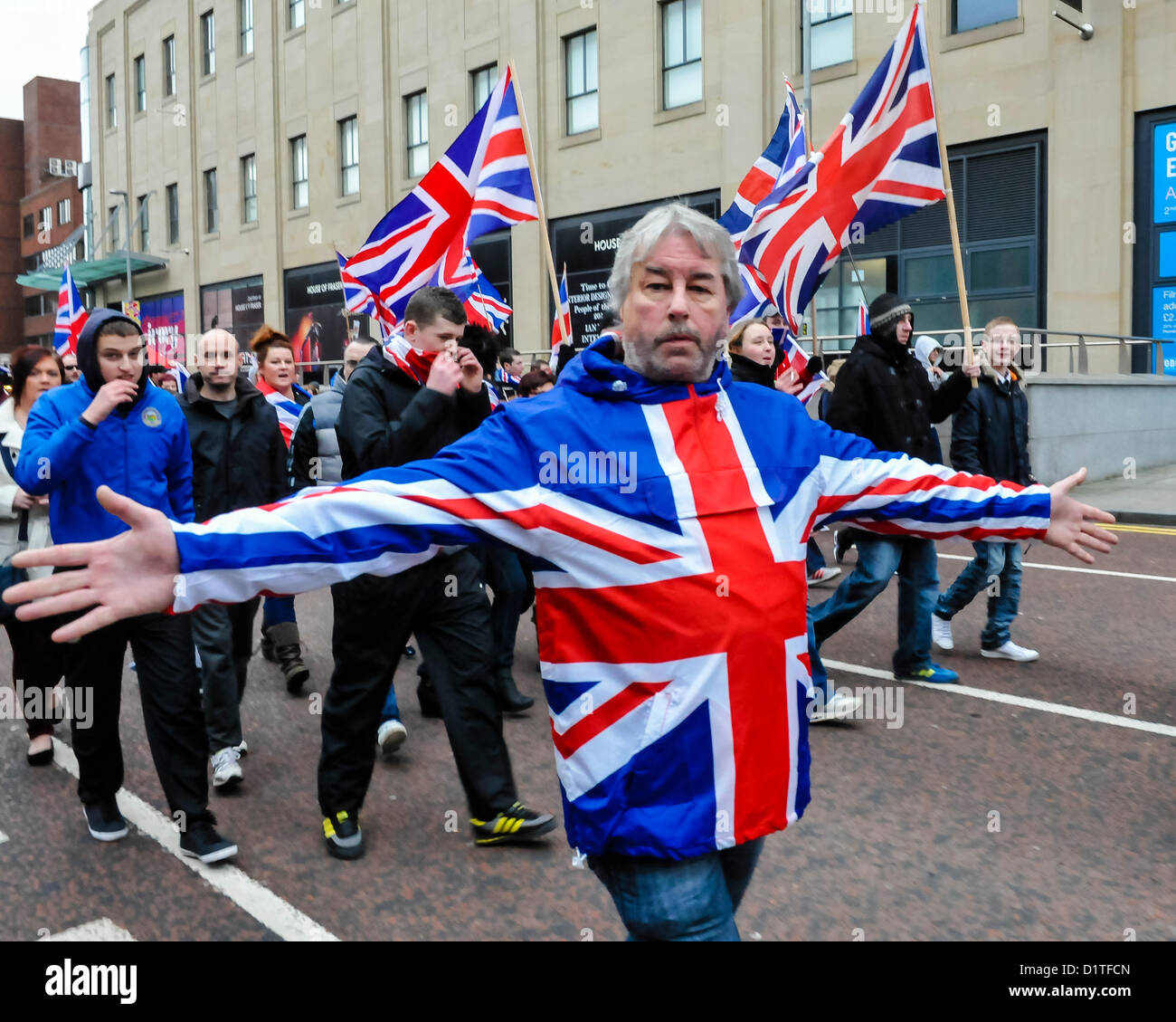 5 janvier 2013. Belfast, en Irlande du Nord - Sam McCrory, Président de la coalition protestante, portant un blouson Union Jack tend les bras pendant qu'il marche avec plus de 1 000 syndicalistes lors d'une solution pacifique, mais tendue, manifestation à Belfast. Les routes ont été fermées pendant environ 60 minutes alors que les manifestants agitaient des drapeaux de l'Union et applaudi. Les manifestations suivez la décision au début de décembre que le drapeau de l'Union européenne ne doit être survolé Belfast City Hall sur 15 jours de «désigné. Banque D'Images