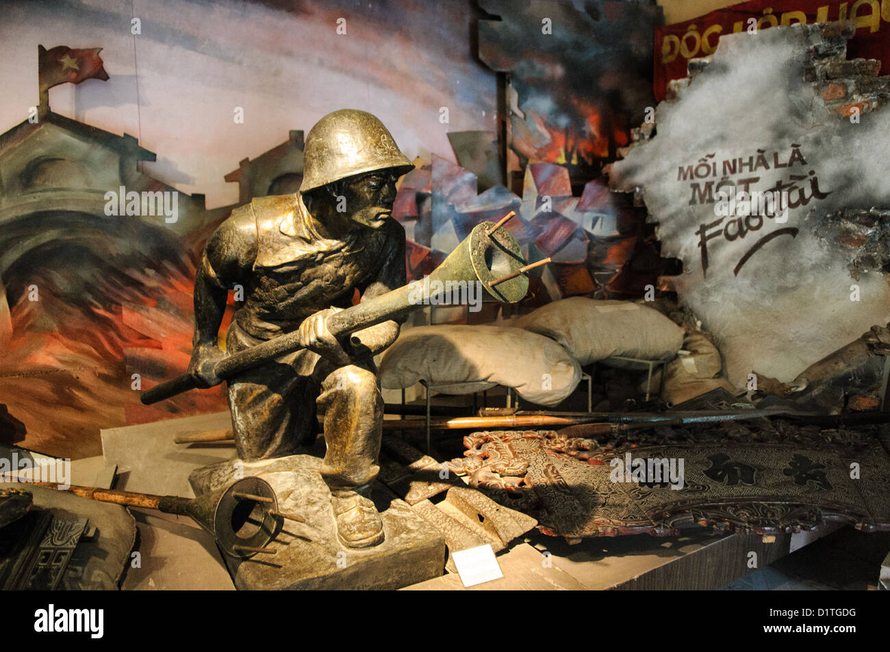 Musée d'histoire militaire du Vietnam Statue en bronze d'un soldat avec mine à lancement Hanoi Vietnam | HANOI, Vietnam — Une statue en bronze au Musée d'histoire militaire du Vietnam représente un soldat Viet Minh brandissant une mine anti-char à lancement. L'inscription peinte du diorama, « Mỗi nhà là một pháo đài » (« Chaque maison est une forteresse »), fait référence à la bataille de Hanoï de 1946–1947. Pendant ce conflit urbain qui a lancé la Première guerre d'Indochine, les combattants utilisaient ces armes suicides munies d'explosifs pour désactiver les blindés français dans les rues barricadées. Banque D'Images