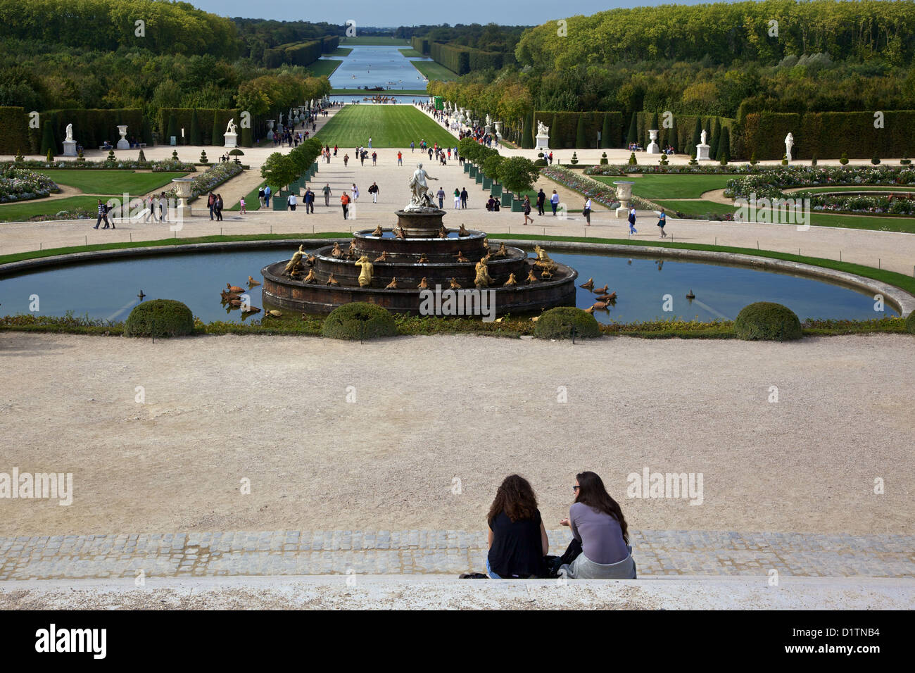 Deux jeunes femmes s'asseoir et parler avec vue sur la Fontaine Latona et jardins du château de Versailles, Paris, France Banque D'Images