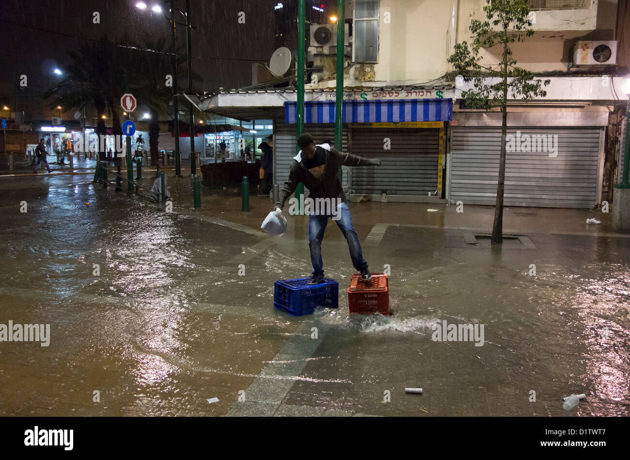 Un migrant africain traversant une rue inondée en un jour de pluie dans le quartier de Neve Shaanan qui est devenu le foyer de l'une des plus grandes populations d'Africains et d'autres migrants dans le sud de tel Aviv Israël Banque D'Images