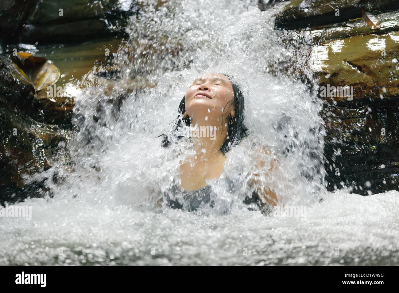 Femme prenant un bain dans une cascade sauvage Banque D'Images