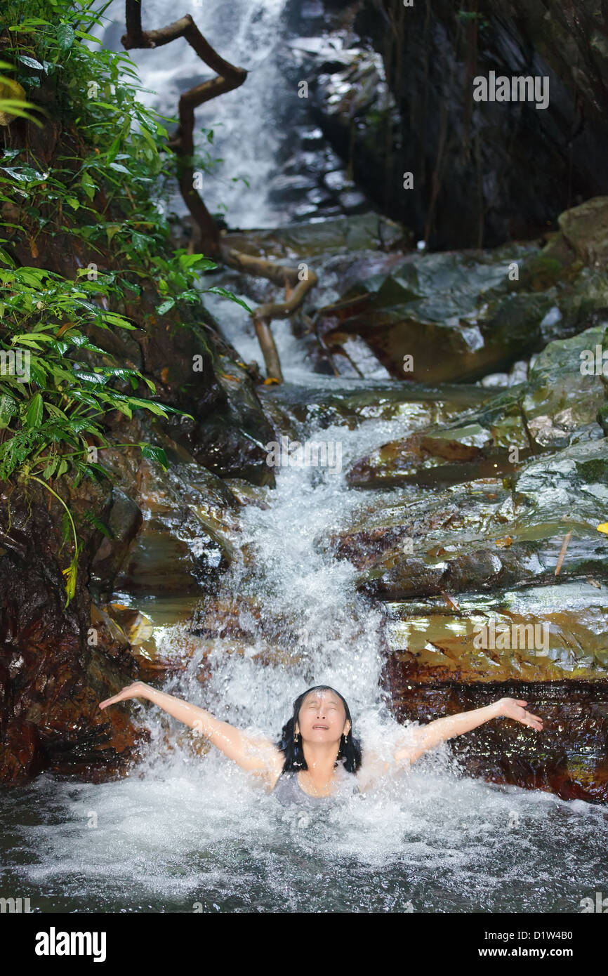 Woman enjoying bath en cascade sauvage, Thaïlande Banque D'Images