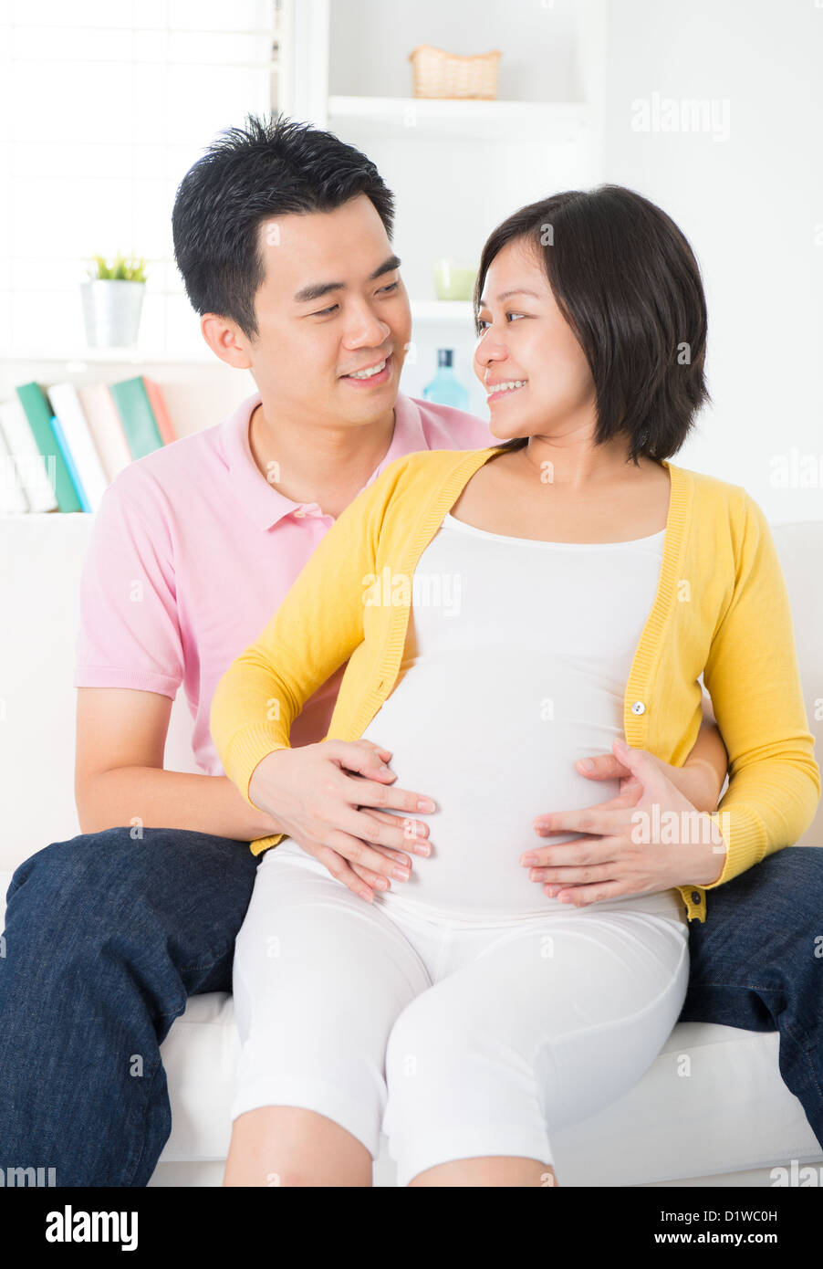 Couple chinois asiatique. Mari et enceinte de 8 mois femme assis sur le canapé Banque D'Images