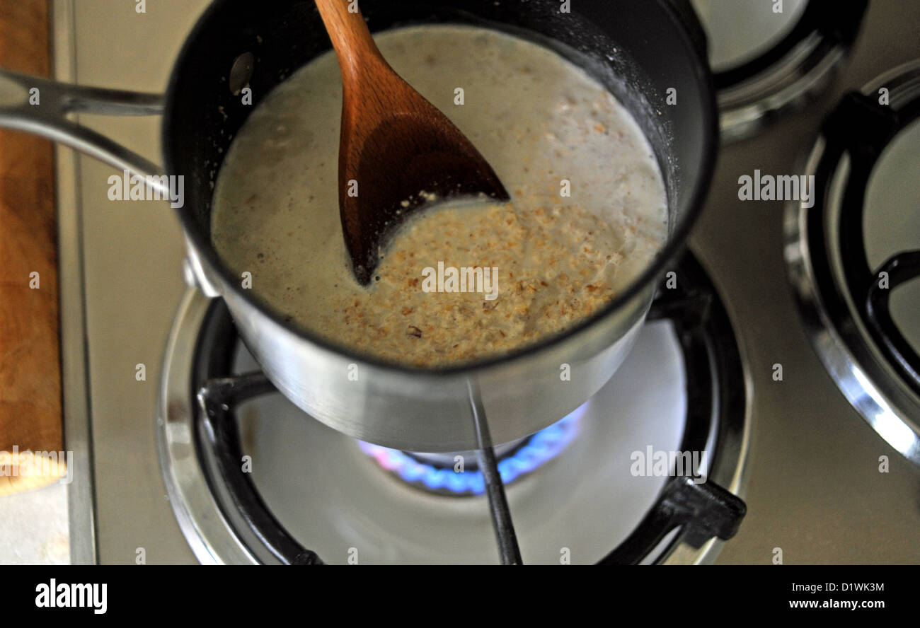 Casserole de porridge d'avoine par cuisson sur une flamme de gaz pour le petit déjeuner Banque D'Images