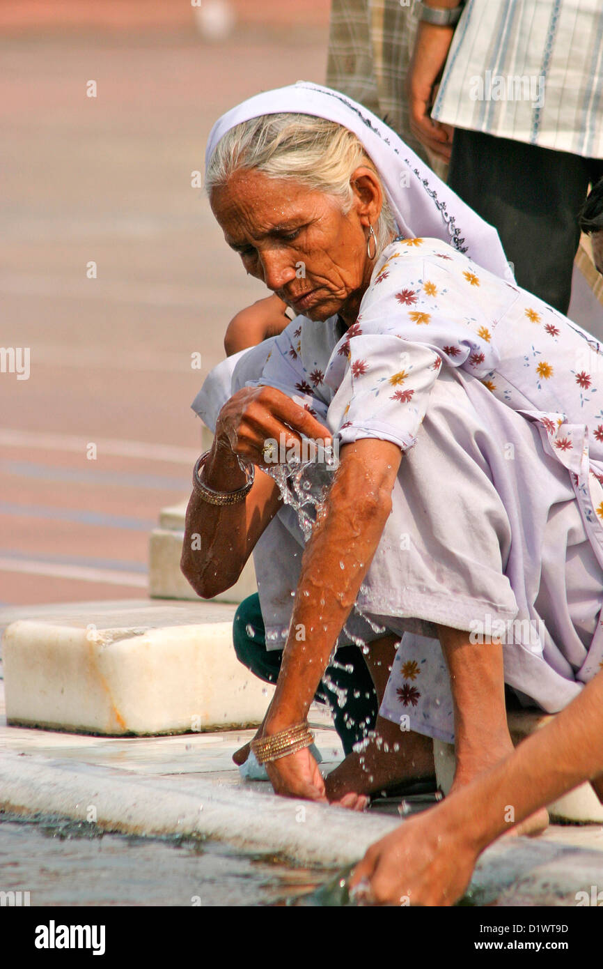 Femme d'effectuer des ablutions rituelles à l'dukka (réservoir d'eau) à la mosquée Jama Mashid à Delhi, en Inde. Banque D'Images