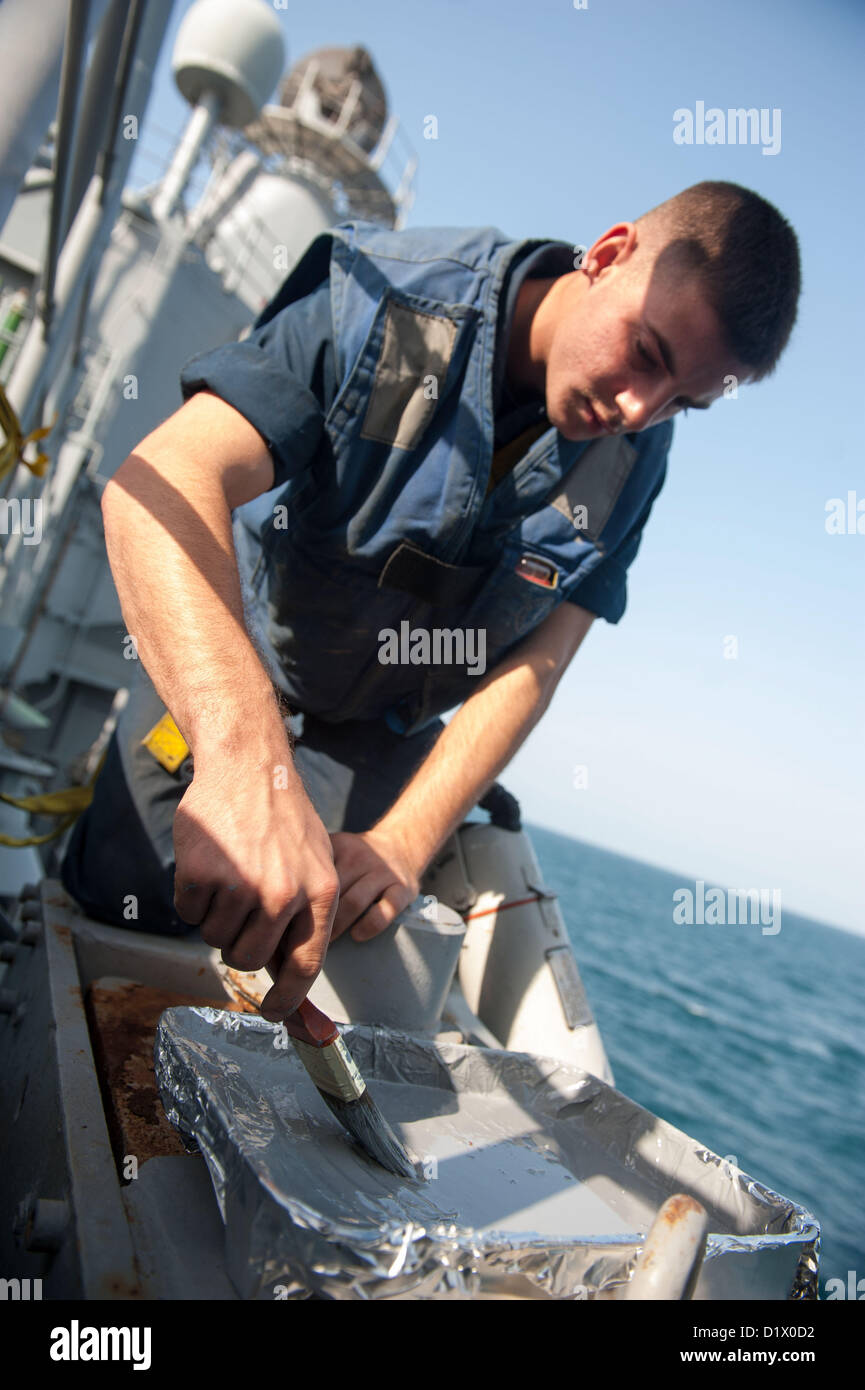 Seaman Michael Brown de El Paso, Texas, travaille sur la peinture à l'aide d'un pinceau en peignant un œil-Patins de glissement à bord de la classe Ticonderoga croiseur lance-missiles USS Mobile Bay (CG 53). La baie de Mobile est déployé avec le John C. Stennis Strike Group pour la 5e Flotte des États-Unis zone de responsabilité des opérations de sécurité maritime, les efforts de coopération en matière de sécurité dans le théâtre et missions d'appui pour l'opération Enduring Freedom.(Janv. 7, 2013) (U.S. Photo par marine Spécialiste de la communication de masse 2e classe Armando Gonzales/libérés) Banque D'Images