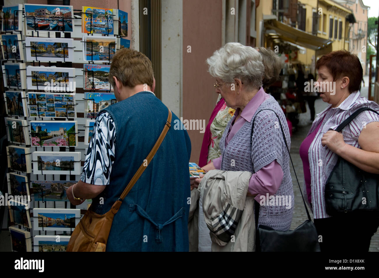 Un groupe de touristes âgés regardant quelques cartes postales pittoresques locales dans une boutique de souvenirs de la ville de Garda du nom du lac de Garde. La petite ville se trouve Banque D'Images