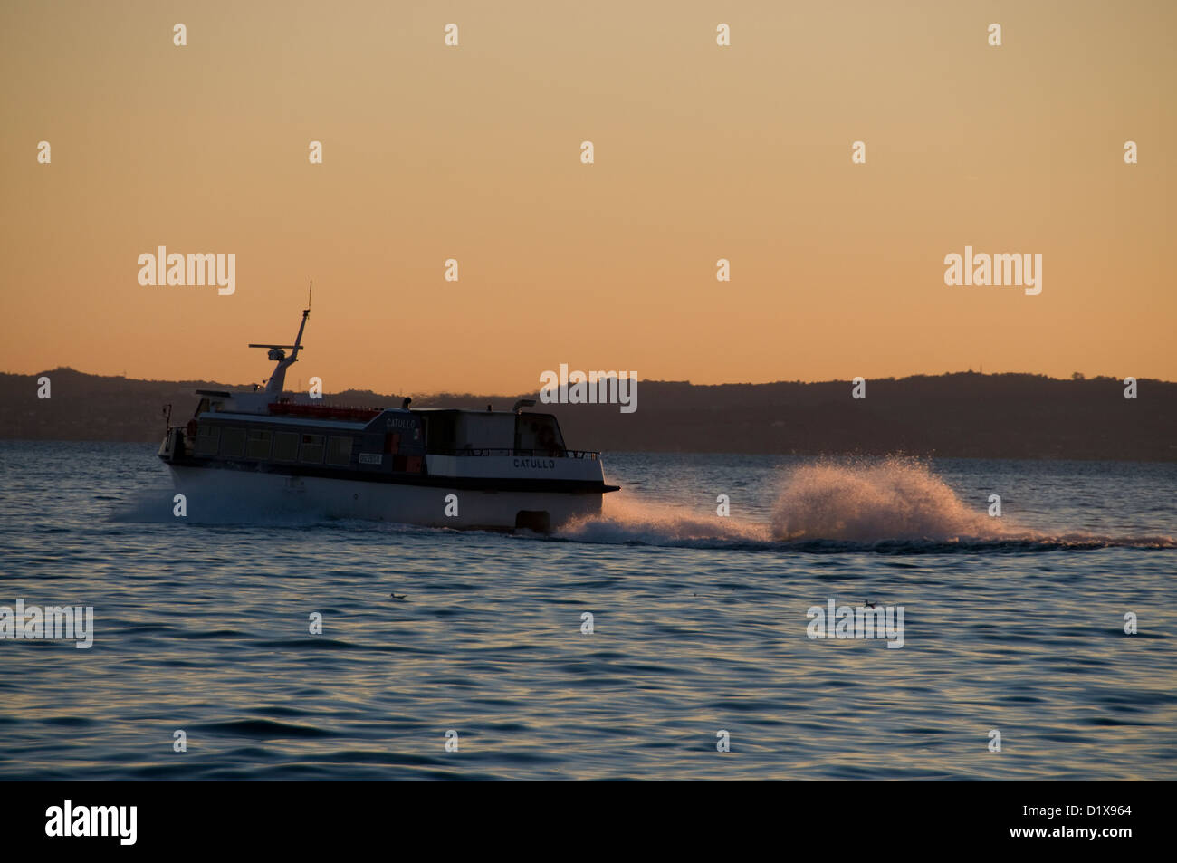 Un ferry pour passagers à grande vitesse sur Garda, au coucher du soleil en Vénétie, Italie Banque D'Images