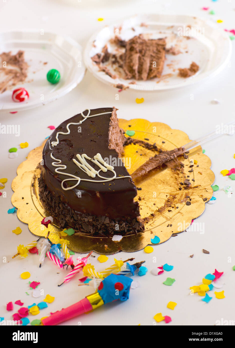 Après la fin de fête d'anniversaire d'enfant avec la moitié des tranches de gâteau au chocolat et confettis Banque D'Images