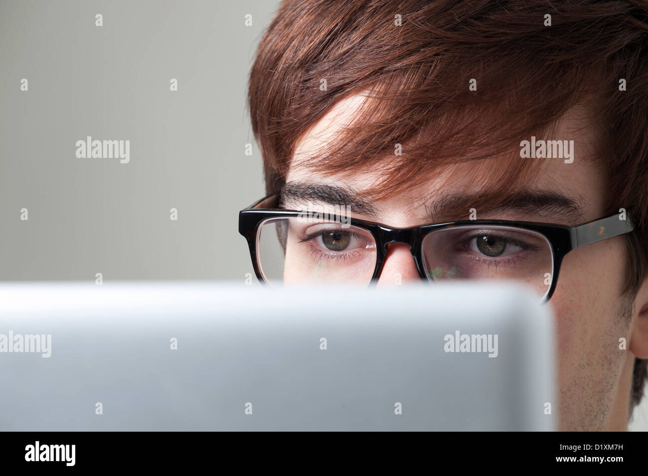 Jeune homme portant des lunettes regarder un écran d'ordinateur. Banque D'Images